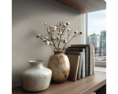 Twee gestructureerde keramieken vazen op een houten plank, één met katoentakken, naast een stapel boeken voor een muur met textuur.