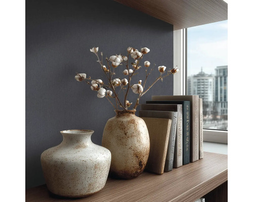 Gestructureerd behang in donkerblauw achter twee keramieken vazen met katoentakken en boeken op een houten plank in een modern, georganiseerd design.