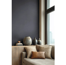 Moderne woonkamer met donkere muurverf, houten dressoir, keramieken vazen en bank met kussens met textuur voor een raam met stadszicht.