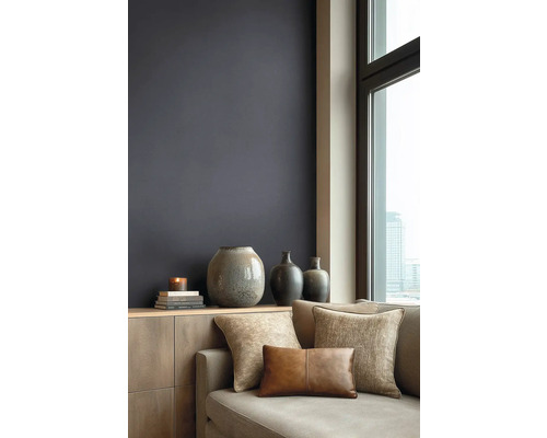 Moderne woonkamer met donkere muurverf, houten dressoir, keramieken vazen en bank met kussens met textuur voor een raam met stadszicht.