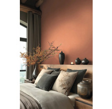 Slaapkamer met bed, kussens, vazen en decoratie in warme tinten