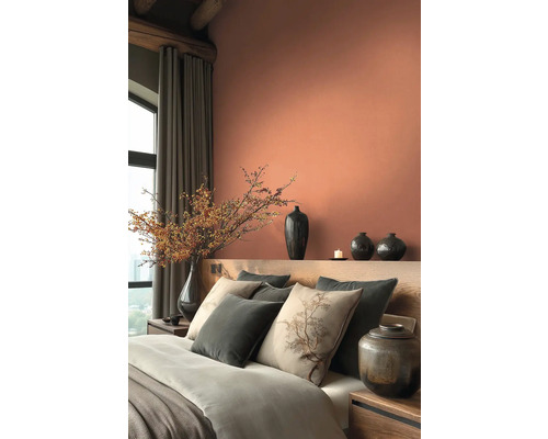 Slaapkamer met bed, kussens, vazen en decoratie in warme tinten