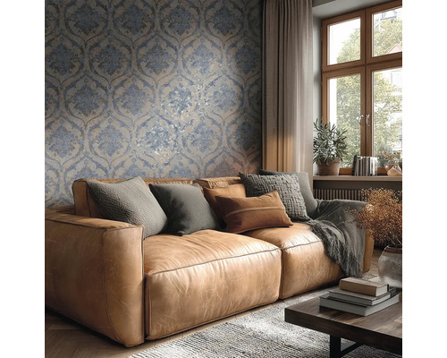 Lichte woonkamer met blauw-beige damastbehang achter een bruine leren bank met kussens en een houten raam.