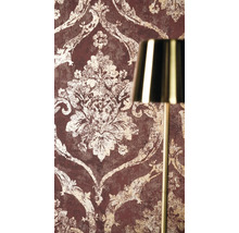 Vliesbehang met barok ornamentpatroon in vintage look naast een gouden lamp.
