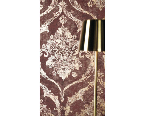 Vliesbehang met barok ornamentpatroon in vintage look naast een gouden lamp.