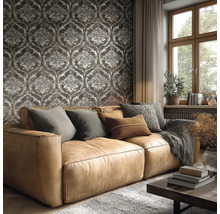 Woonkamer met een bruine leren bank voor donker behang met barokke ornamenten, een groot raam en een gezellige inrichting.