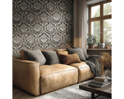 Woonkamer met een bruine leren bank voor donker behang met barokke ornamenten, een groot raam en een gezellige inrichting.