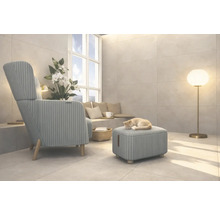 Woonkamer met fauteuil, voetenbank, vloerlamp en een kat die op de voetenbank slaapt