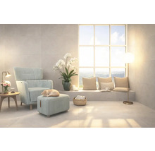 Lichte woonkamer met fauteuil, voetenbank en groot raam