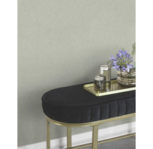 Close-up van een wand met subtiel behang en een bank met decoratie