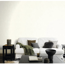 Woonkamer met witte bank, kussens, deken en donkere salontafel