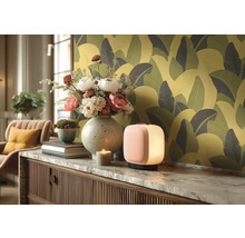 Decoratieve woonsfeer met tafellamp, bloemen, kaars en behang met print.