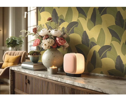 Decoratieve woonsfeer met tafellamp, bloemen, kaars en behang met print.