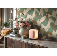 Moderne kamer met behang met groot bladmotief. Op een dressoir met marmeren blad staan een tafellamp, een vaas met bloemen en decoratie.