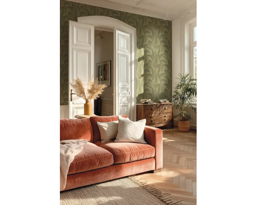 Woonkamer met groen behang met bladmotief, terracotta fluwelen bank en visgraatparket in helder licht.