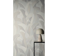 Vliesbehang met groot bladpatroon achter een moderne tafellamp op een metalen tafel.