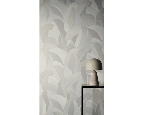 Vliesbehang met groot bladpatroon achter een moderne tafellamp op een metalen tafel.