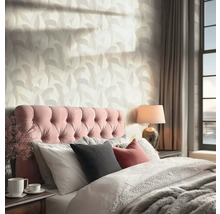 Behang met abstract bladpatroon in een lichte slaapkamer met gecapitonneerd hoofdbord en venster.