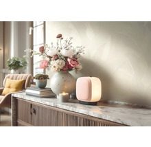 Moderne tafellamp op een dressoir met marmeren blad naast een bloemenvaas en een kaars in een lichte, georganiseerde woonkamer.