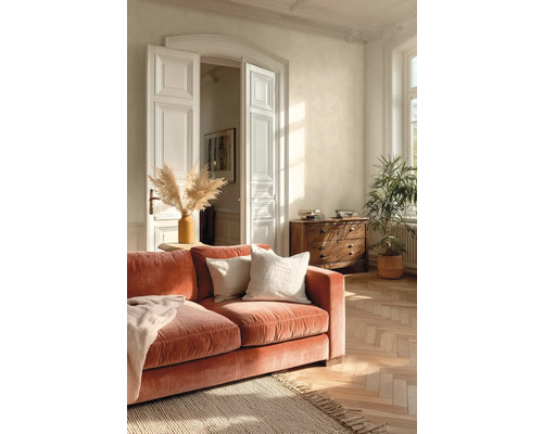 Lichte woonkamer met terracotta fluwelen bank, houten visgraatparket, witte openslaande deuren en een massief houten ladekast.