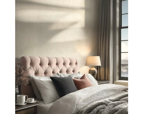 Lichte slaapkamer met gecapitonneerd hoofdbord, beddengoed met textuur, een tafellamp en schaduwen van zonlicht op de muur.