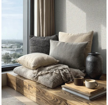 Gezellige zithoek op een houten bank bij het raam met kussens, een geweven deken, een vaas en koffiemokken op een dienblad.