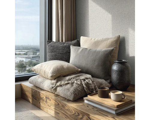 Gezellige zithoek op een houten bank bij het raam met kussens, een geweven deken, een vaas en koffiemokken op een dienblad.