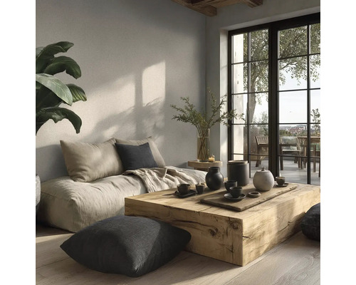 Lichte woonkamer met massieve houten tafel, lage vloerbank, kussens en grote ramen in minimalistische stijl met natuurlijke wandafwerking.