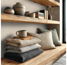 Wanddecoratie met gestructureerd vliesbehang met linnenlook, gecombineerd met massief houten planken, keramiek en zachte gebreide dekens.