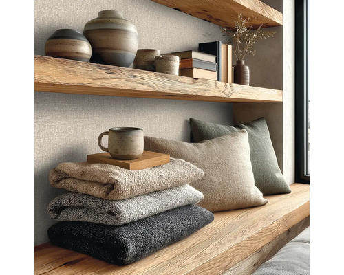 Wanddecoratie met gestructureerd vliesbehang met linnenlook, gecombineerd met massief houten planken, keramiek en zachte gebreide dekens.