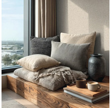 Gezellige zithoek bij het raam met houten bank, diverse kussens, wollen deken, vaas en dienblad met koffiekopjes op boeken.