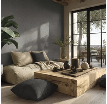 Lichte woonkamer met zitkussens, houten tafel en decoratie tegen een gestructureerde muur