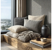 Decoratieve kussens en een deken op een houten bank bij een raam met uitzicht