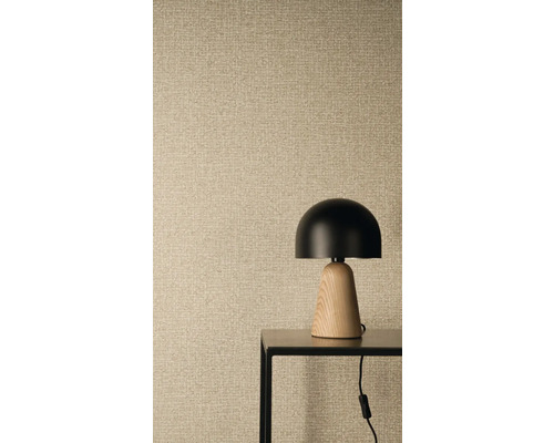 Vliesbehang met linnenstructuur en geweven look, op de voorgrond een moderne tafellamp met zwarte kap en houten voet op een metalen tafel.