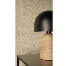 Moderne tafellamp met een zwarte koepelkap en houten voet voor getextureerd behang met een geweven look.