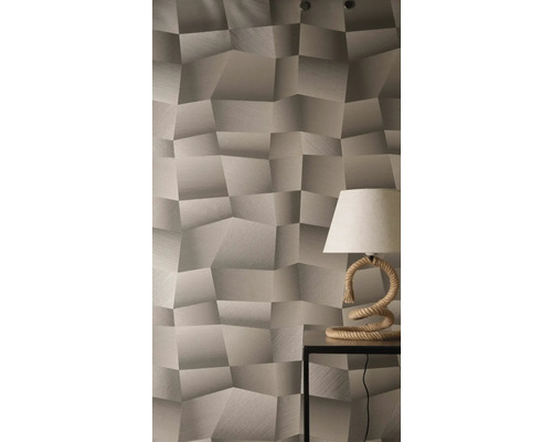 Behang met driedimensionaal geometrisch patroon en gestructureerd oppervlak, gecombineerd met een tafellamp met touwvoet op een bijzettafel.