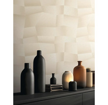 Behang met geometrisch driedimensionaal patroon in beige op een muur achter een dressoir met verschillende vazen.