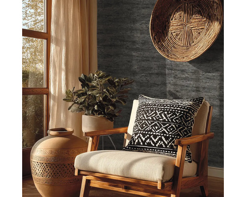 Donkergrijs behang met steenlook in een rustiek ingerichte woonkamer met houten stoel, terracotta vaas en kamerplant.