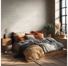 Lichte slaapkamer met bed op houten platform, veel kussens en kamerplanten.