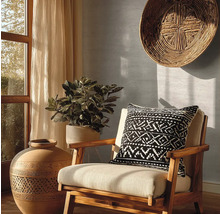 Decoratief interieur met een stoel, een kussen met geometrisch patroon, een grote vaas en een kamerplant.