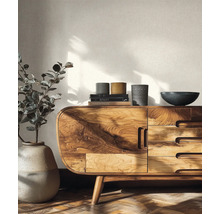 Lichte woonkamer met een massief houten dressoir, een grote vloervaas met plant en gestructureerd behang.