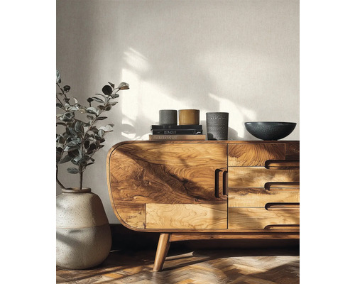 Lichte woonkamer met een massief houten dressoir, een grote vloervaas met plant en gestructureerd behang.