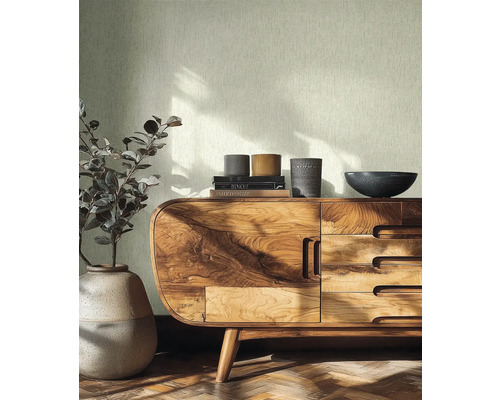 Licht structuurbehang in een lichte kamer met houten dressoir, keramische vaas en parketvloer.