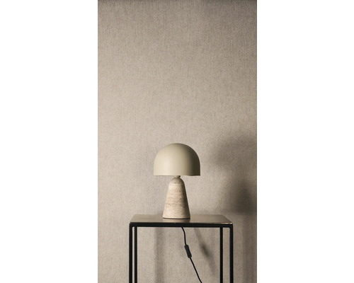 Tafellamp met halfronde kap en kegelvormige stenen voet op een zwarte bijzettafel voor een wand met textuur.
