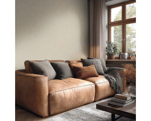 Gezellige woonkamer met bruine leren bank, kussens, beige structuurbehang en houten raam.