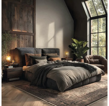 Modern rustieke slaapkamer met gestoffeerd bed, houten wandpanelen, leren fauteuil, grote groene plant en visgraatparket.