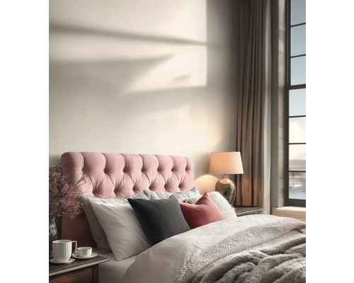 Licht ingerichte slaapkamer met gecapitonneerd hoofdbord, kussens, dekbed met textuur, tafellamp en gordijnen bij het raam.