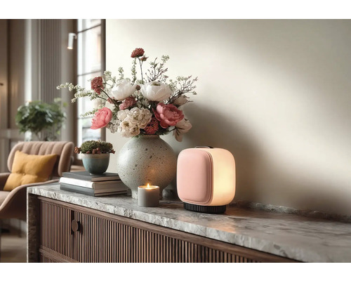 Moderne draagbare LED-lamp, stenen vaas met bloemen en een kaars op een dressoir met marmeren blad in een lichte woonkamer.