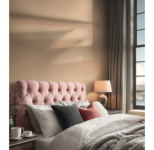 Een slaapkamer met een bed, een gestoffeerd hoofdeinde, kussens, een lamp en gordijnen.