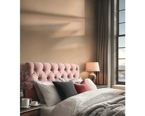 Een slaapkamer met een bed, een gestoffeerd hoofdeinde, kussens, een lamp en gordijnen.